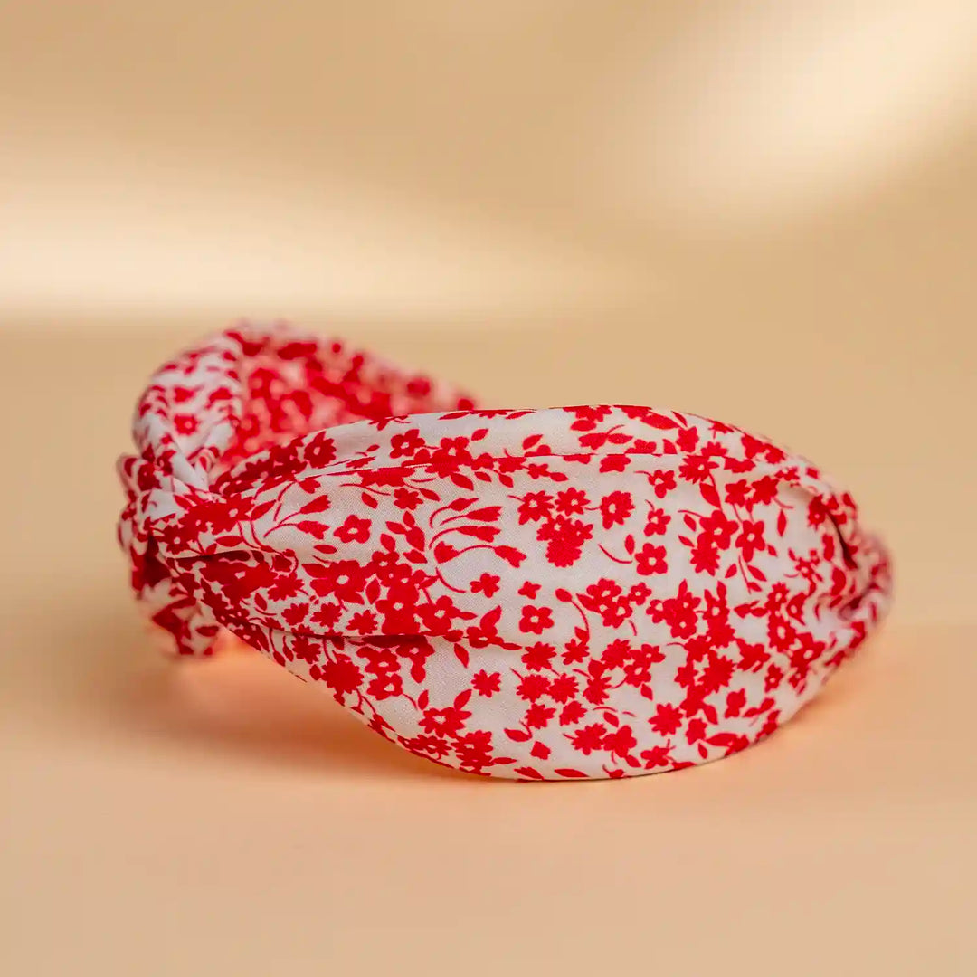 Lucys red and white simple floral headband. White background with simple red floral pattern. Side view.